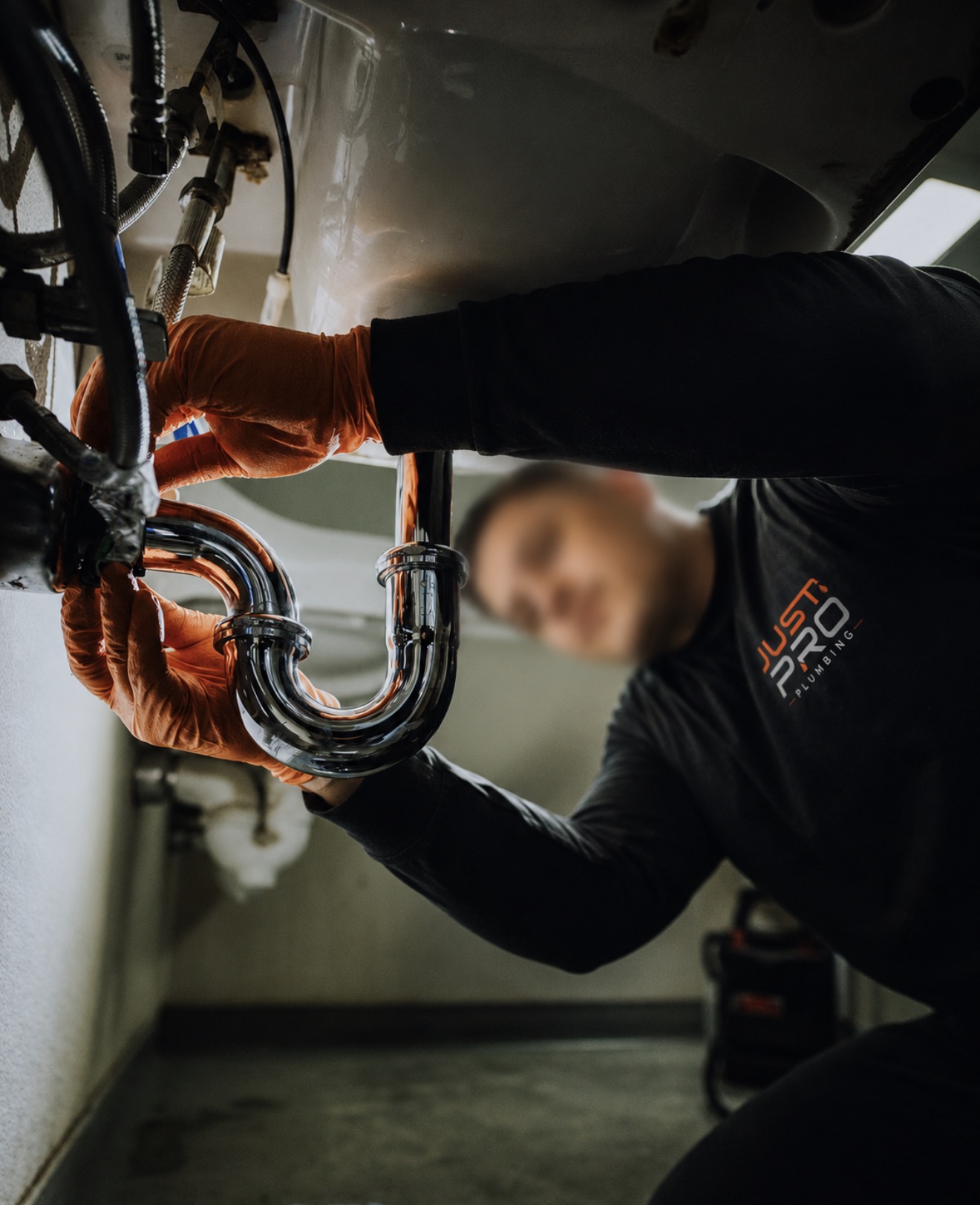 Just Pro Plumbing technician in branded workwear working on pipework